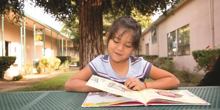 A girl reads outside at a picnic table A girl reads outside at a picnic table
