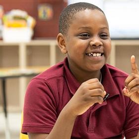 A young boy counts with his hands by holding up one finger. A young boy counts with his hands by holding up one finger.