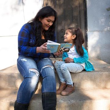 A mother reads a book to her child outside A mother reads a book to her child outside