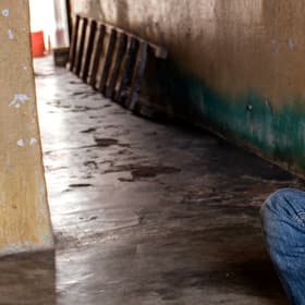 A young boy sits alone on the floor in an empty corridor. A young boy sits alone on the floor in an empty corridor.