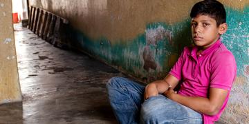 A young boy sits alone on the floor in an empty corridor. A young boy sits alone on the floor in an empty corridor.