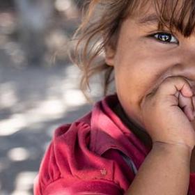 A two-year old girl puts a thumb in her mouth while sitting on her mother’s lap outside on the street. A two-year old girl puts a thumb in her mouth while sitting on her mother’s lap outside on the street.