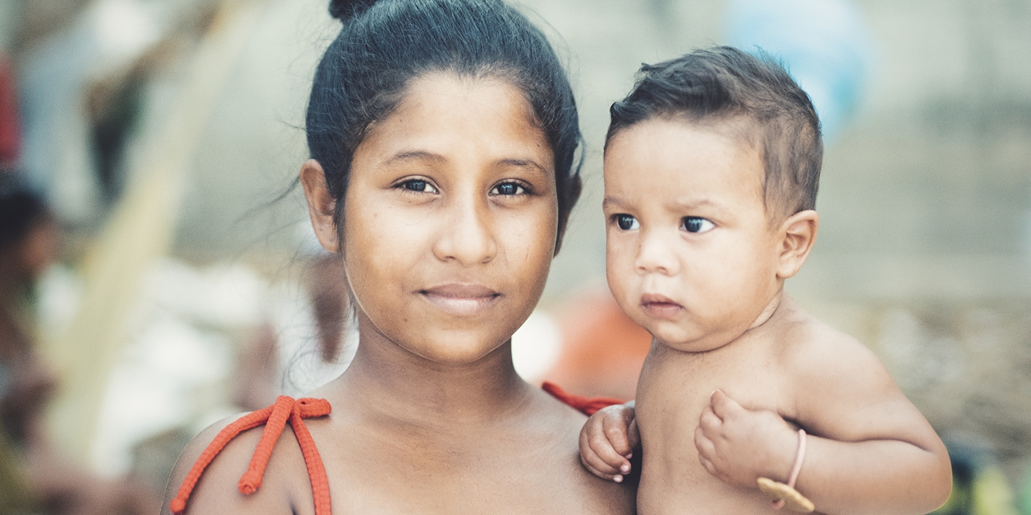 Venezuela, a young mother holding her baby look at the camera Venezuela, a young mother holding her baby look at the camera