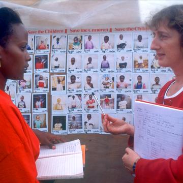 Save the Children staff stand in front of a Polaroid photo board used as part of the Save the Children's mass tracing programme after the Rwandan genocide. The immense scale of children separated from their families after the Rwandan genocide in 1994 (April - June) prompted the international community to make efforts to reunify children and relatives from the earliest stages. Photo Credit: Jenny Matthews/Save the Children 1995. Save the Children staff stand in front of a Polaroid photo board used as part of the Save the Children's mass tracing programme after the Rwandan genocide. The immense scale of children separated from their families after the Rwandan genocide in 1994 (April - June) prompted the international community to make efforts to reunify children and relatives from the earliest stages. Photo Credit: Jenny Matthews/Save the Children 1995.