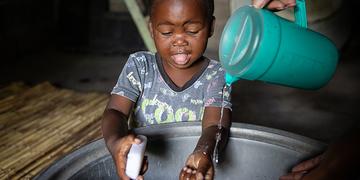 A toddler washes his hands in a basin in Zambia A toddler washes his hands in a basin in Zambia